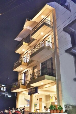 A multi-story building with balconies, a ground-level entrance, and a sign for 'Blue Jay.' - The Blue Jay Hostel Rishikesh (Narendranagar)