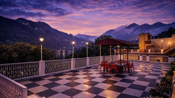 A terrace with a checkered floor, outdoor seating, and a view of mountains.
