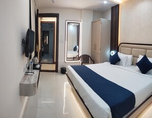 A hotel room with a bed, a TV, a mirror, a wardrobe, and a bathroom visible through an open door. - Hotel Aranyasutra Inaya Indore (Indore)