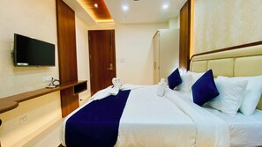 A hotel room with a bed, a TV, a wardrobe, and a door. - Hotel Aranyasutra Inaya Indore (Indore)