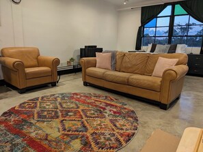 Una sala de estar con sofá, sillón y alfombra redonda.