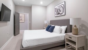 Ein Schlafzimmer mit einem Bett, Nachttischen, einem Fernseher und einem Bild an der Wand.