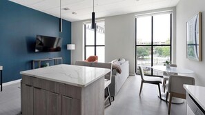 A modern kitchen with a marble countertop, a built-in oven, and a large window.