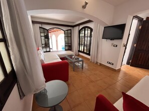 A living room with a sofa, a coffee table, and a TV mounted on the wall. - El Pacha Suites Sharm Sanafir Hotel (Sharm El Sheikh)