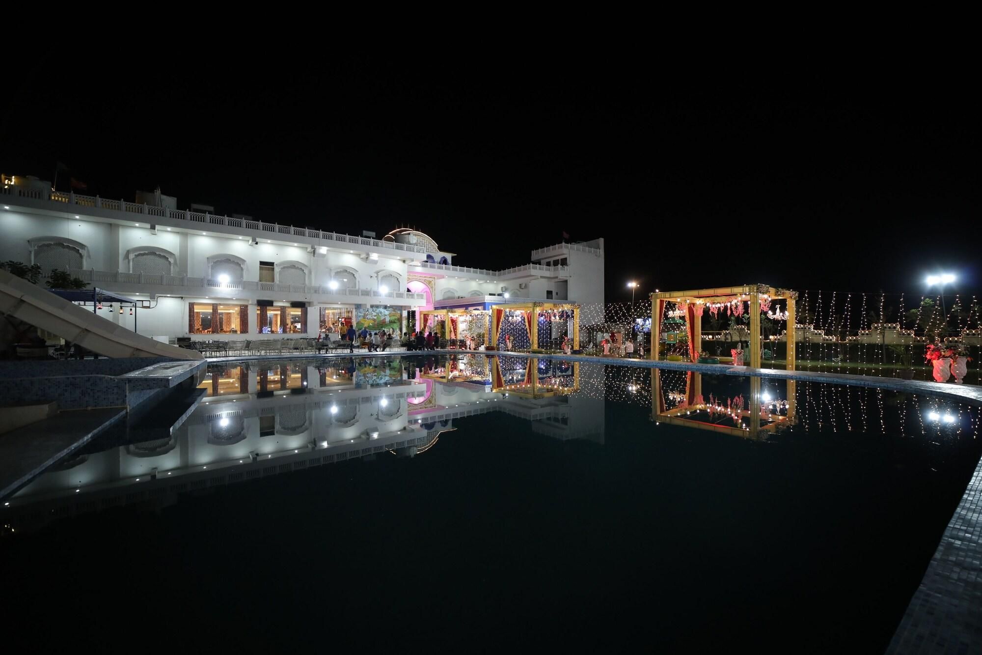 Un hotel con piscina que refleja el edificio y una zona cubierta con luces.