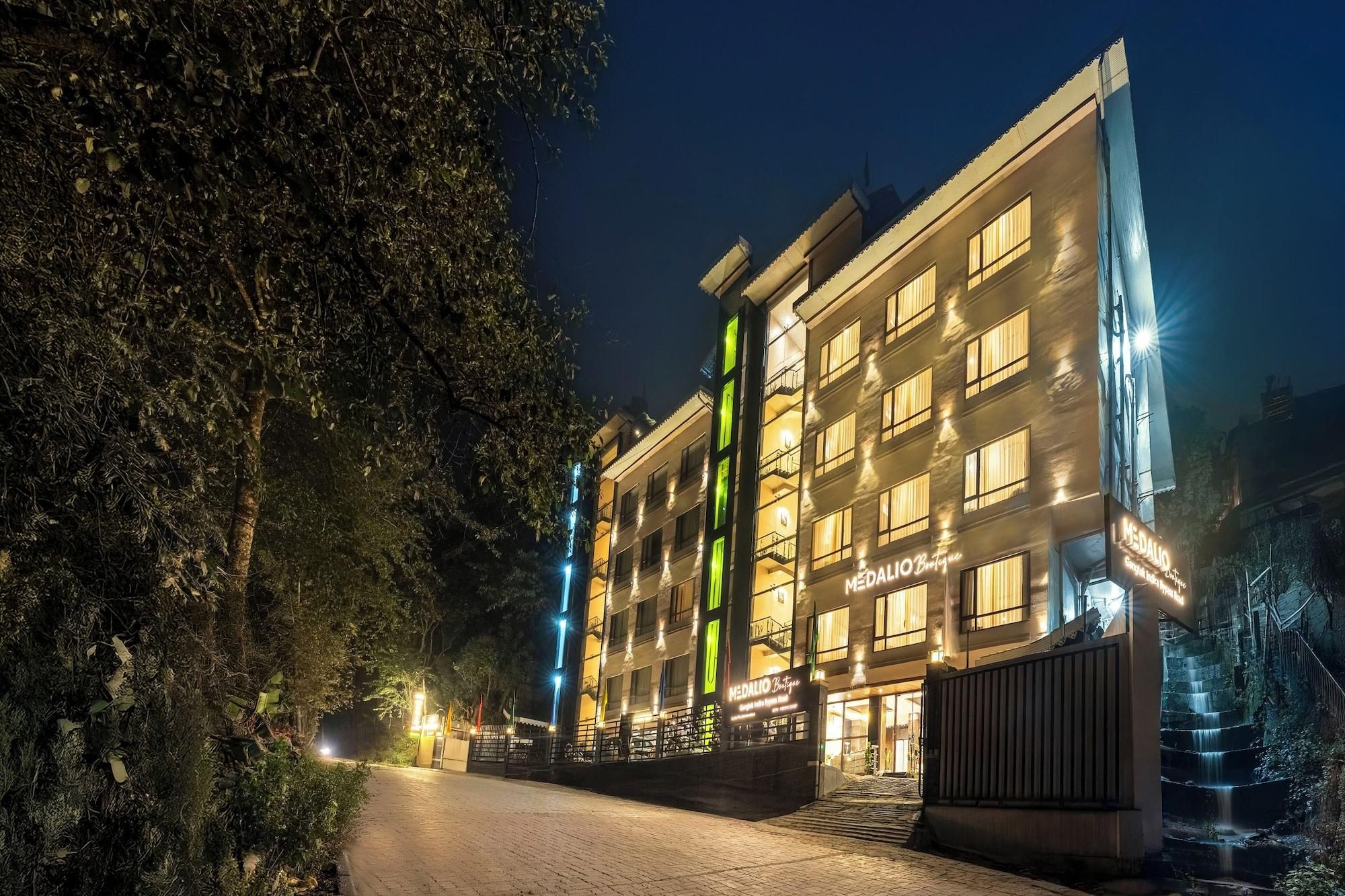 Een meerlaags hotel met een opvallend verticaal groen lichtelement, een goed verlichte ingang en een hekpoort.