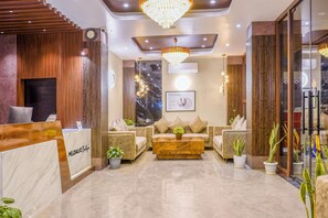 A hotel lobby with a reception desk, seating area, chandeliers, and plants. - Medalio Boutique Orbit International (Gangtok)