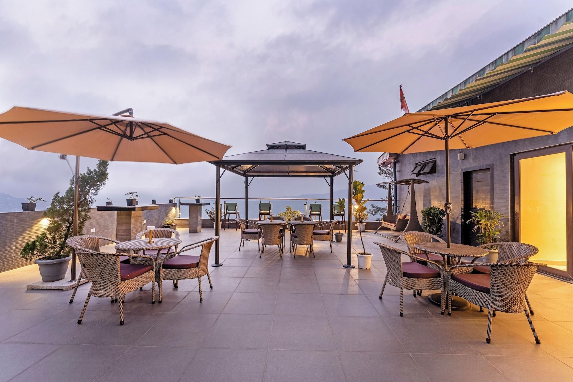 An outdoor patio with wicker furniture, umbrellas, and a view of the sea.