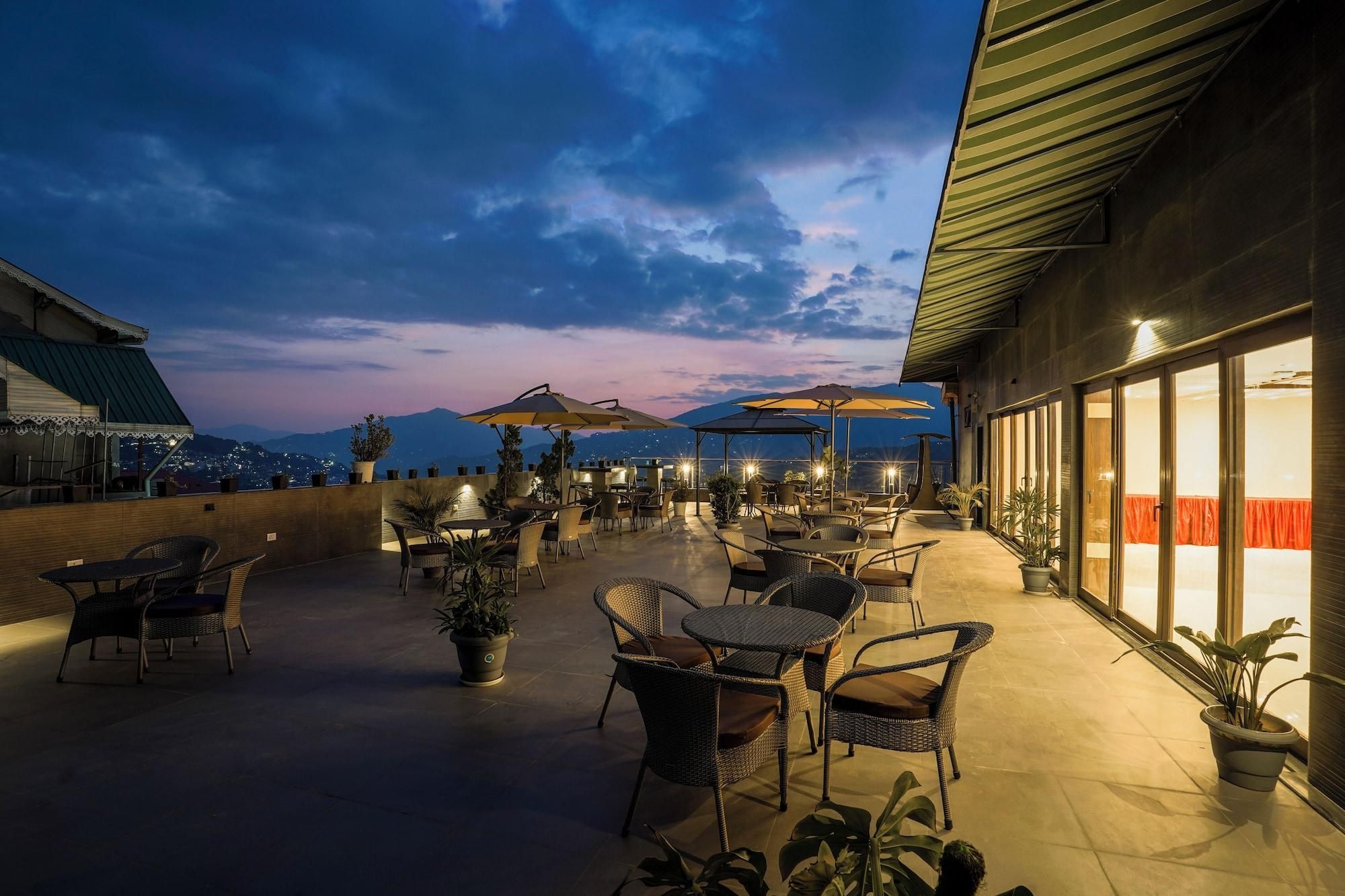 Een terras buiten met tafels, stoelen, parasols en plantenpotten.