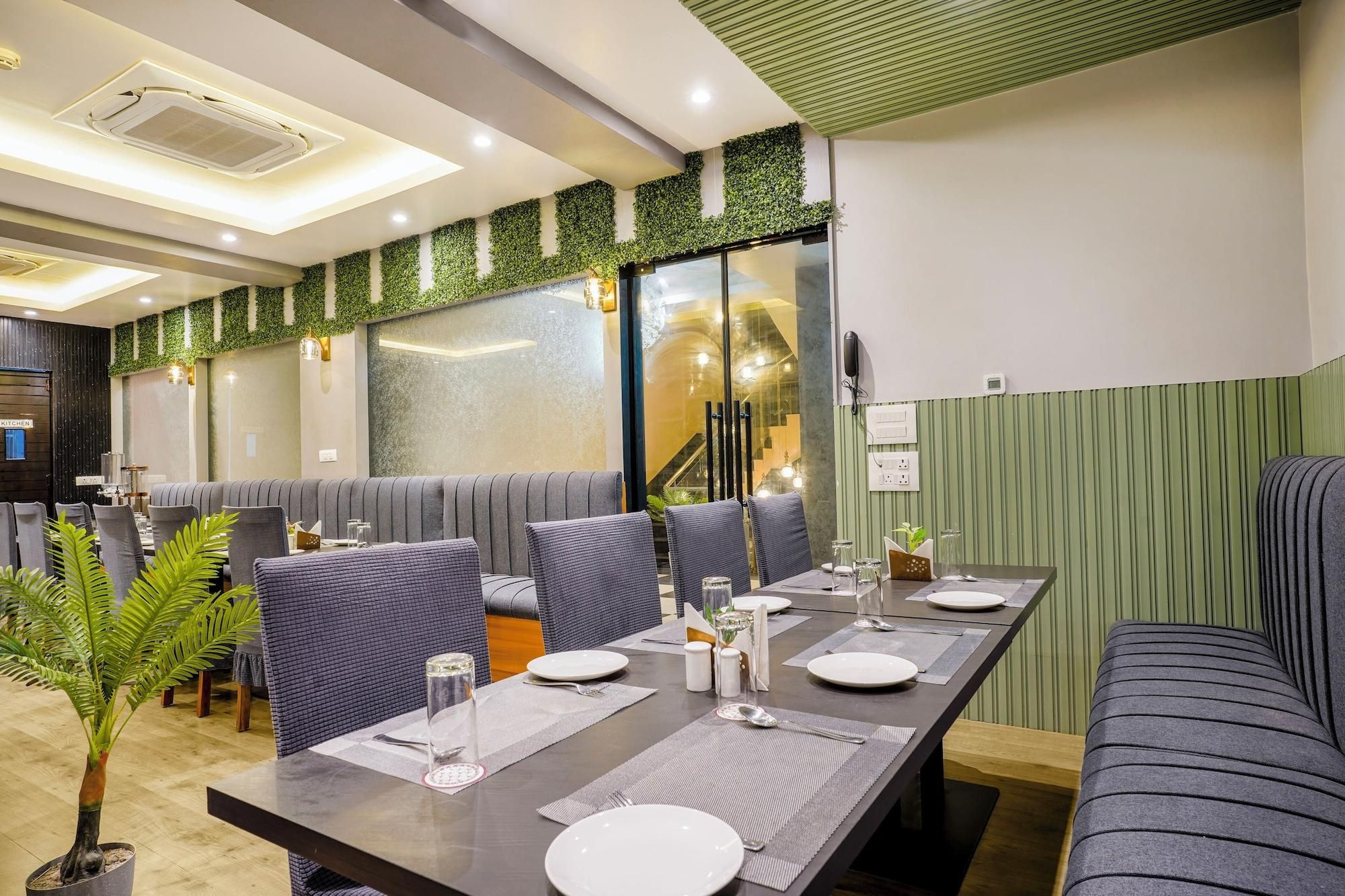 A restaurant with a long dining table, cushioned seating, and a kitchen area in the background.