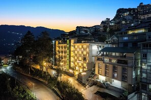 A multi-story hotel with a central courtyard, surrounded by trees and a winding road. - Medalio Boutique Orbit International (Gangtok)