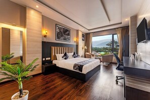 Una habitación de hotel moderna con una cama grande, un escritorio, una silla y vistas al exterior.