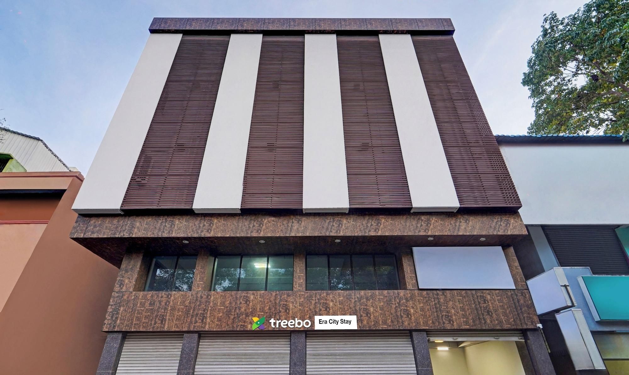 A modern building with a flat roof, large windows, and a sign for 'treebo Era City Stay'.