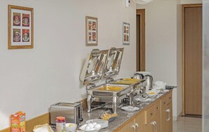 A buffet setup with various food items, a toaster, and a refrigerator.