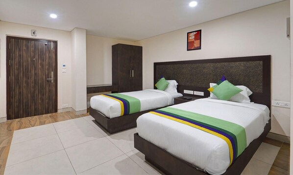 A hotel room with two beds, a wardrobe, and a painting on the wall. - Treebo Vetri Supreme Residency (Chennai)