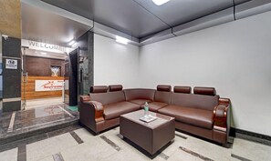 A modern lobby with a brown leather sofa, a coffee table, and a reception desk with a 'WELCOME' sign. - Treebo Vetri Supreme Residency (Chennai)