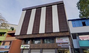 A multi-story building with a modern architectural design, featuring a prominent entrance with a sign for 'Supreme Residency' and another sign for 'treebo'.