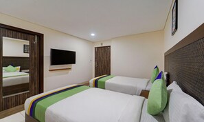 A hotel room with two beds, a television mounted on the wall, and a door with a mirror. - Treebo Vetri Supreme Residency (Chennai)