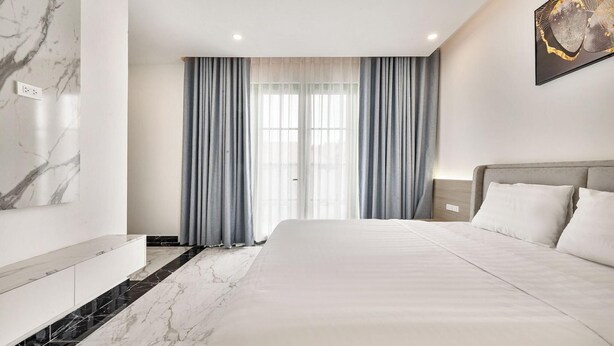 Een moderne hotelkamer met een groot bed, marmeren vloer en uitzicht op het buitengebied door het raam.