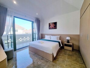 Ein Hotelzimmer mit Bett, Nachttisch, einem Gemälde und Blick ins Freie.