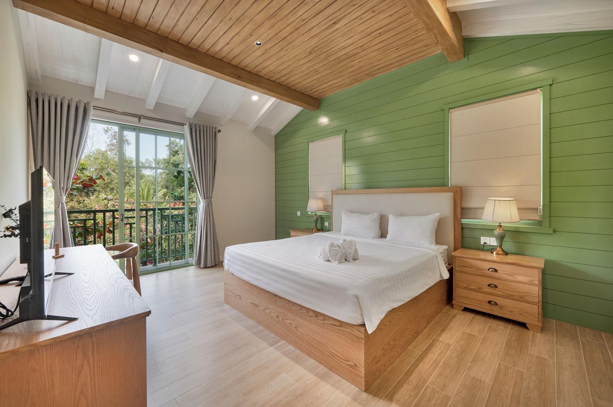 Een slaapkamer met een bed, nachtkastjes, een bureau en een balkon.