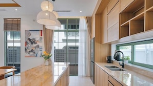 Een moderne keuken met een marmeren aanrecht, houten kastjes, een inbouwoven en een raam met uitzicht op de stad.