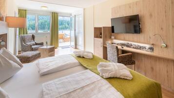 Een hotelkamer met een bed, bureau, stoel, televisie en uitzicht op de omgeving.