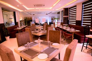 Ein Restaurant mit mehreren Speisetischen, gepolsterten Stühlen und modernem Interieur.
