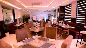A restaurant with multiple dining tables, cushioned chairs, and a modern interior design. - D Pavillon Boutique Hotel Delhi Airport (New Delhi)