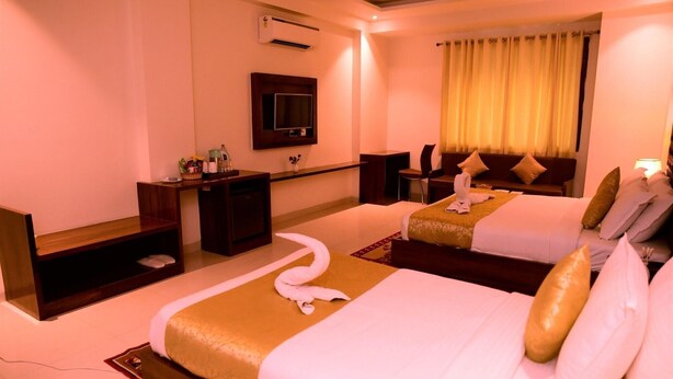 A hotel room with two beds, a desk, a chair, a TV, and an air conditioning unit. - D Pavillon Boutique Hotel Delhi Airport (New Delhi)