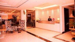 A hotel reception area with a reception desk, a waiting area with chairs, and a dining area in the background. - D Pavillon Boutique Hotel Delhi Airport (New Delhi)