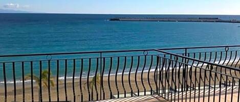 A balcony with two sun loungers and a view of the ocean.