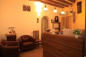 A reception area with a wooden reception desk, two leather chairs, a wooden bench, a wall-mounted clock, and a framed picture.