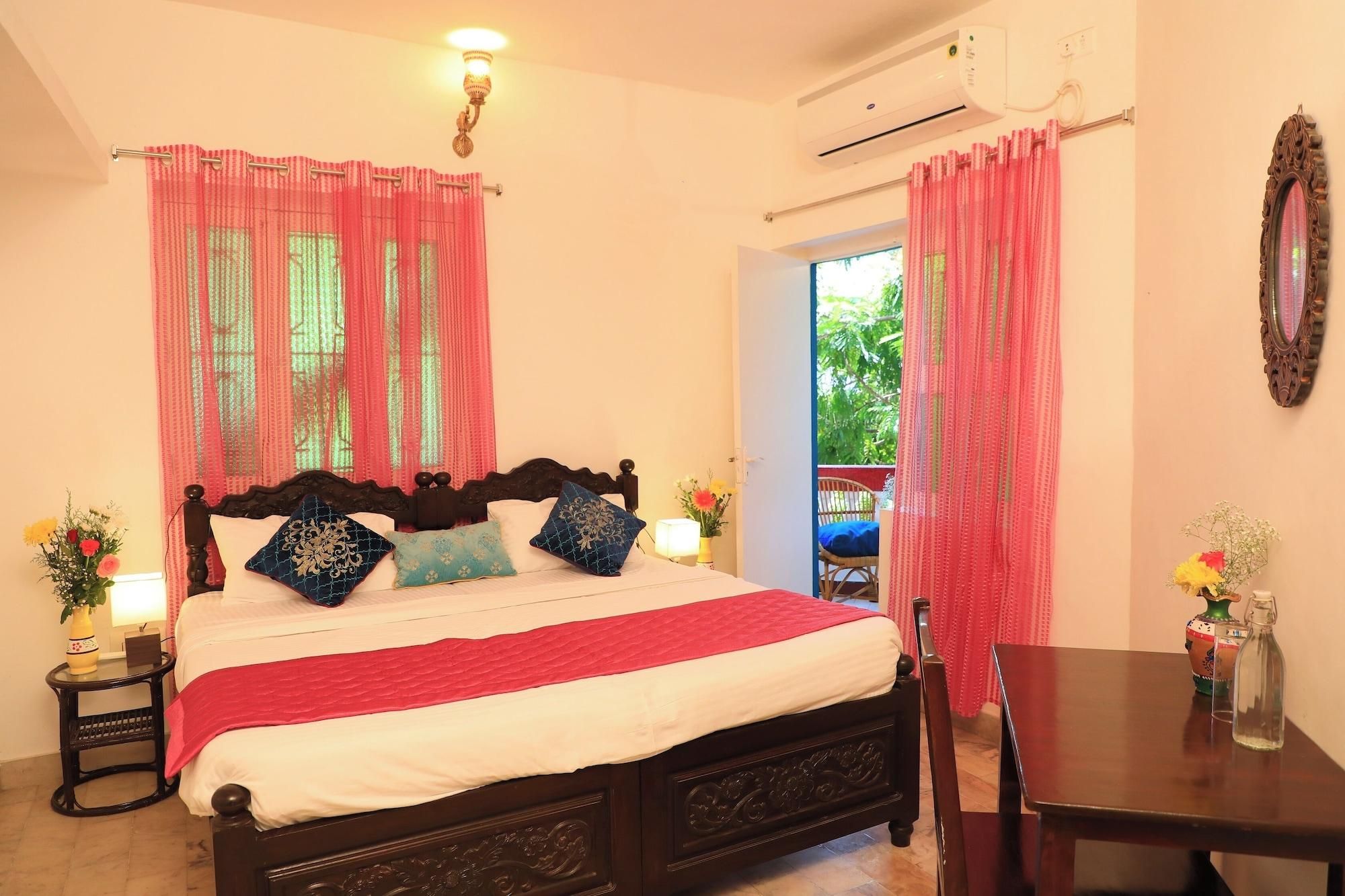 A bedroom with a bed, bedside tables, a mirror, and a view of the outdoors.