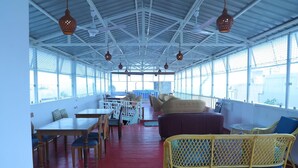 A covered outdoor seating area with tables and chairs, a red floor, and hanging pendant lights. - Le Clarisse Guest House (Chennai)