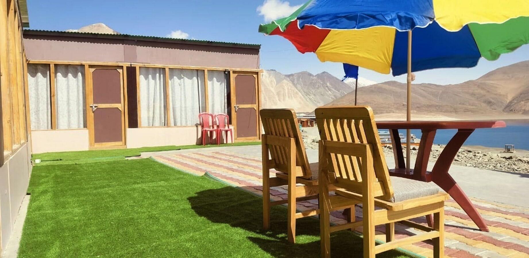 A patio with a table and chairs, a small lawn, and a building with windows and doors.