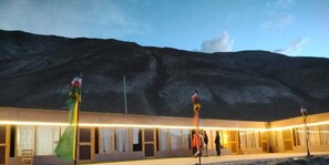 A building with a flat roof and a long, narrow structure with multiple windows. - Grand Cozy Cottage Pangong (Leh)