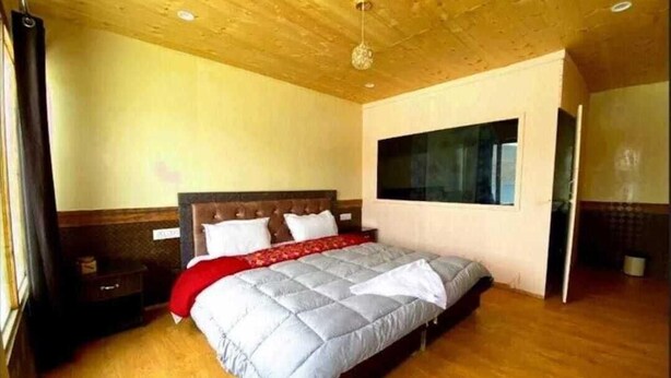 Quarto com cama, assoalho de madeira, janela e porta.