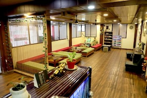 Una habitación tradicional japonesa con suelo de tatami, mesas de madera baja y cojines rojos.
