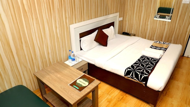 Una habitación de hotel con cama, mesita de noche y un escritorio pequeño con un cuaderno.