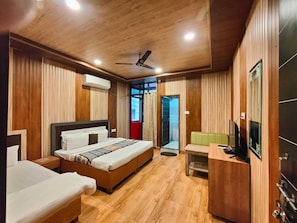 Habitación de hotel con techo de madera, una cama, un escritorio y un televisor.