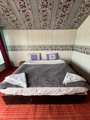 Un lit avec une couvre-lit à motifs, deux oreillers et un plafond décoratif.