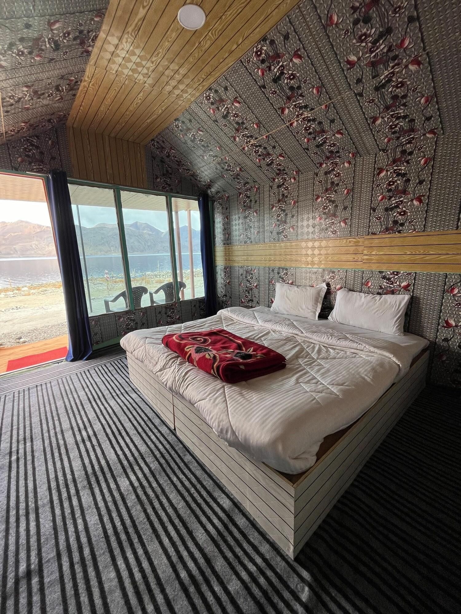 A bedroom with a large bed, a window with a view, and a patterned ceiling.