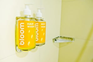 Two bottles of hair and body wash on a wall-mounted shelf in a bathroom. - Bloom Hotel - Cyber Towers (Hyderabad)