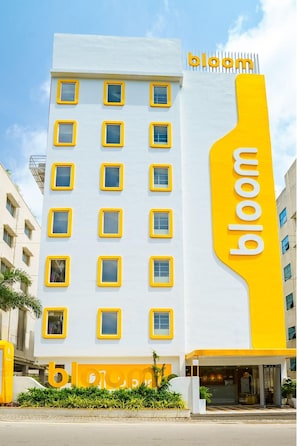 A building with a white facade and yellow accents, featuring a prominent 'bloom' sign. - Bloom Hotel - Cyber Towers (Hyderabad)