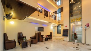 A spacious lobby with leather seating, a flat-screen TV, and a large clock. - Hotel Arch Inn (Jaipur)