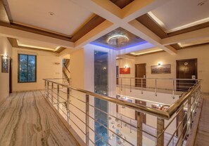 A spacious interior with a high ceiling, a central chandelier, and a staircase leading to an upper level. - Hotel Arch Inn (Jaipur)