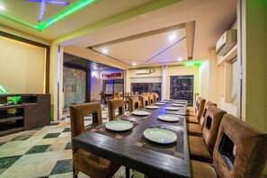 Een restaurant met een lange tafel, stoelen en een geruite vloer.
