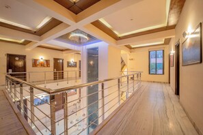 A spacious hotel lobby with a high ceiling, a glass railing, and a marble floor. - Hotel Arch Inn (Jaipur)