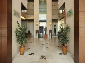 Een hotellobby met een receptiebalie, potplanten en een bord met 'Beach Inn'.